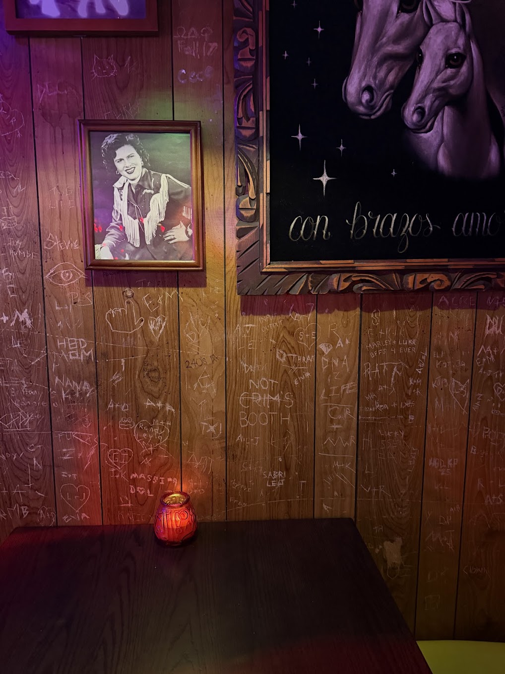 Honky-tonk booth with carved wood paneling, framed portraits, and a candle at Meow Wolf Houston