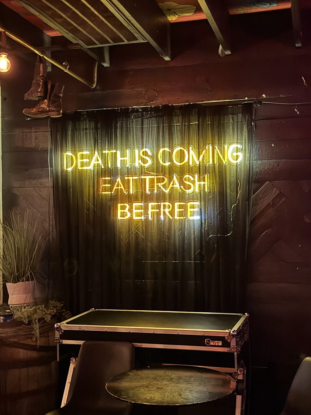 Neon sign reading DEATH IS COMING EAT TRASH BE FREE at Meow Wolf Houston